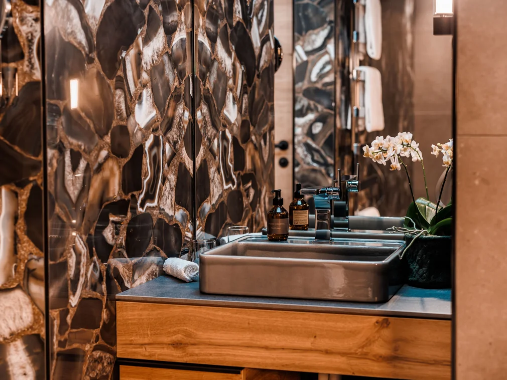Modern bathroom sink with marble wall and orchid plant