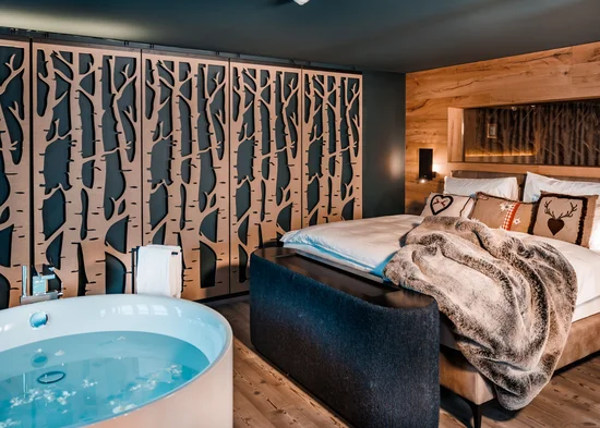 Flitterwochen im Hotel in Österreich | Schlosshotel Kitzbühel Gemütliches Schlafzimmer mit Whirlpool und Holzdekor