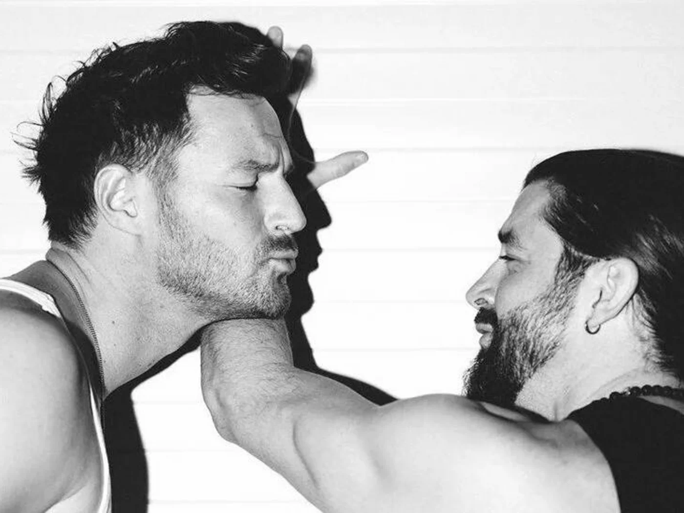 Close-up of two men, one kissing the other's arm