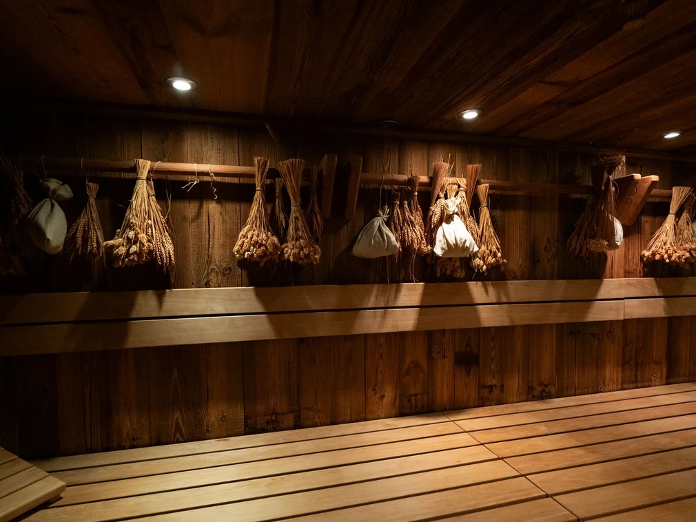 Wooden sauna with bundles of dried herbs hanging and spot lighting