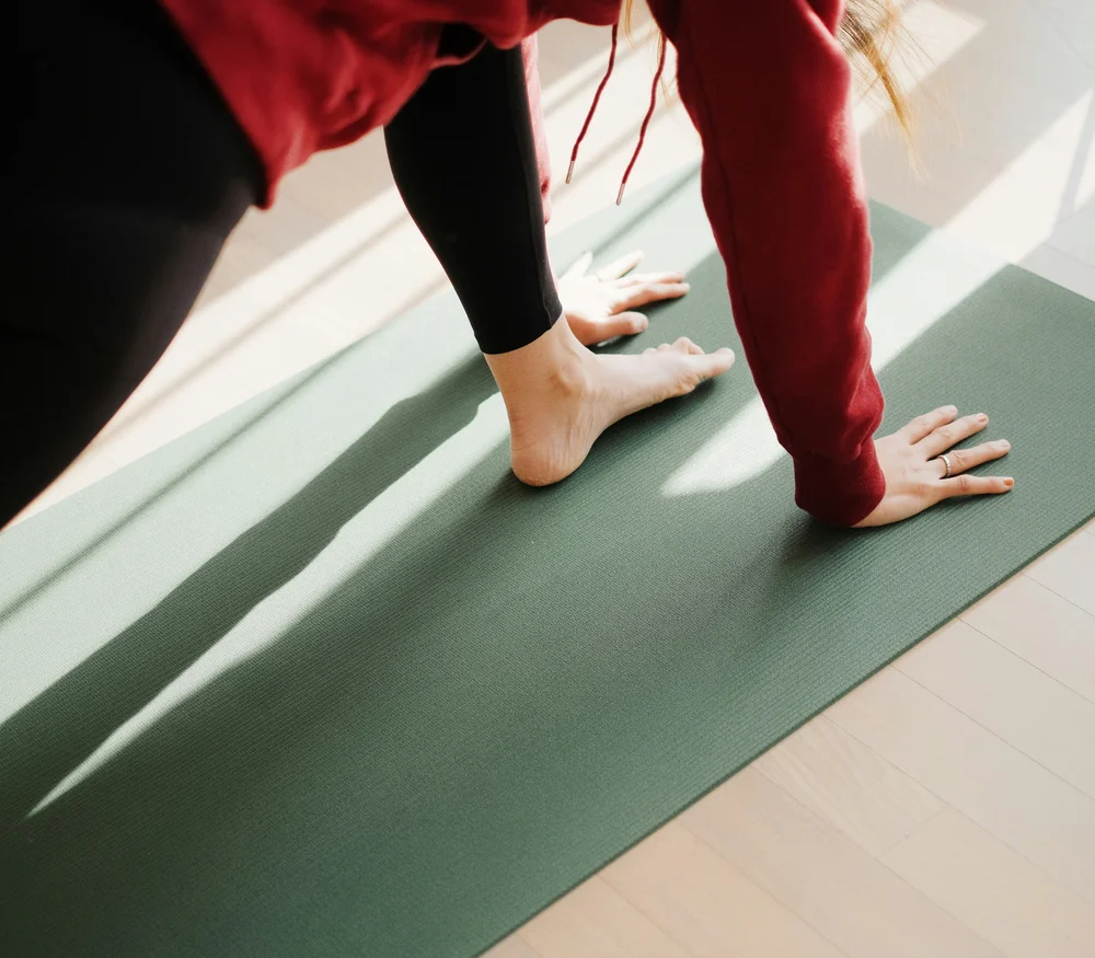 Person doing yoga on a mat in the sunlight