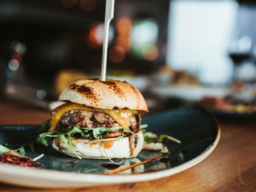 Small cheeseburger with lettuce on a plate in a restaurant