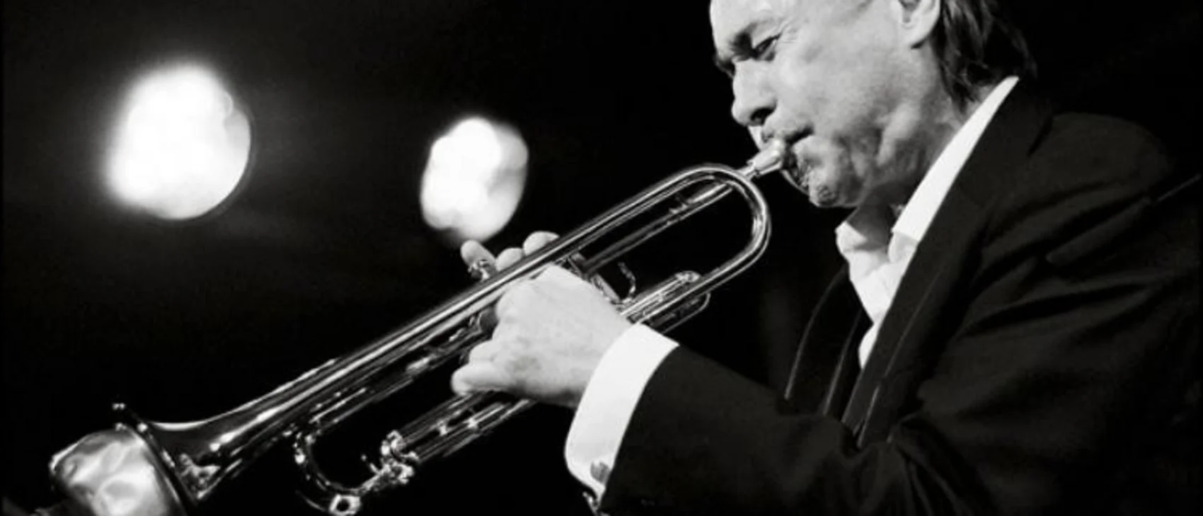 Schwarzweißbild eines Mannes im Anzug, der Trompete spielt