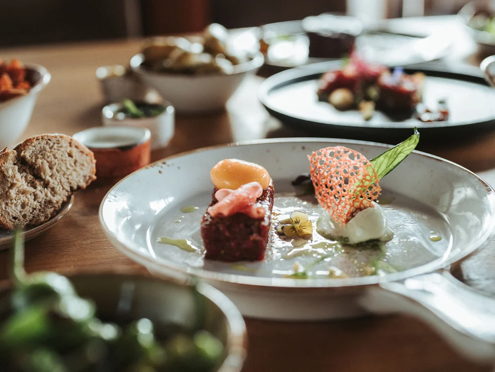 Finely plated dish with bread and vegetable salads on wooden table