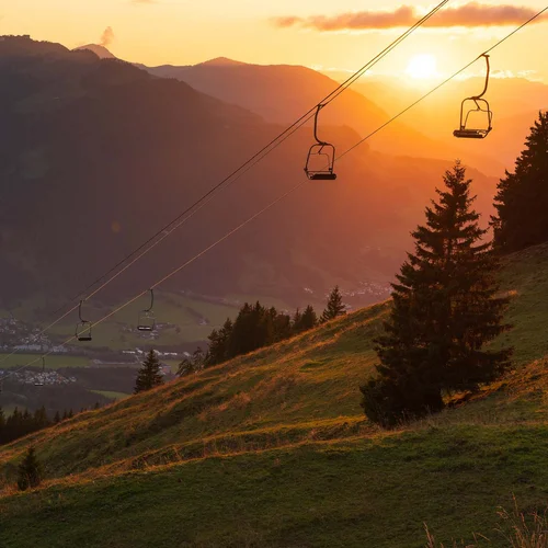 Sonnenuntergang über Bergen mit Sessellift und Tal darunter