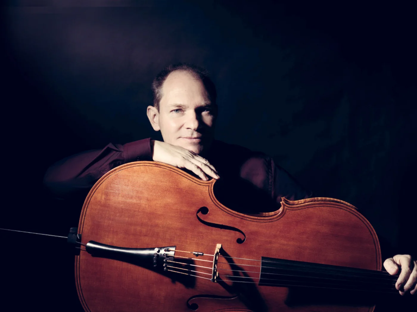 Man with a cello against a dark background