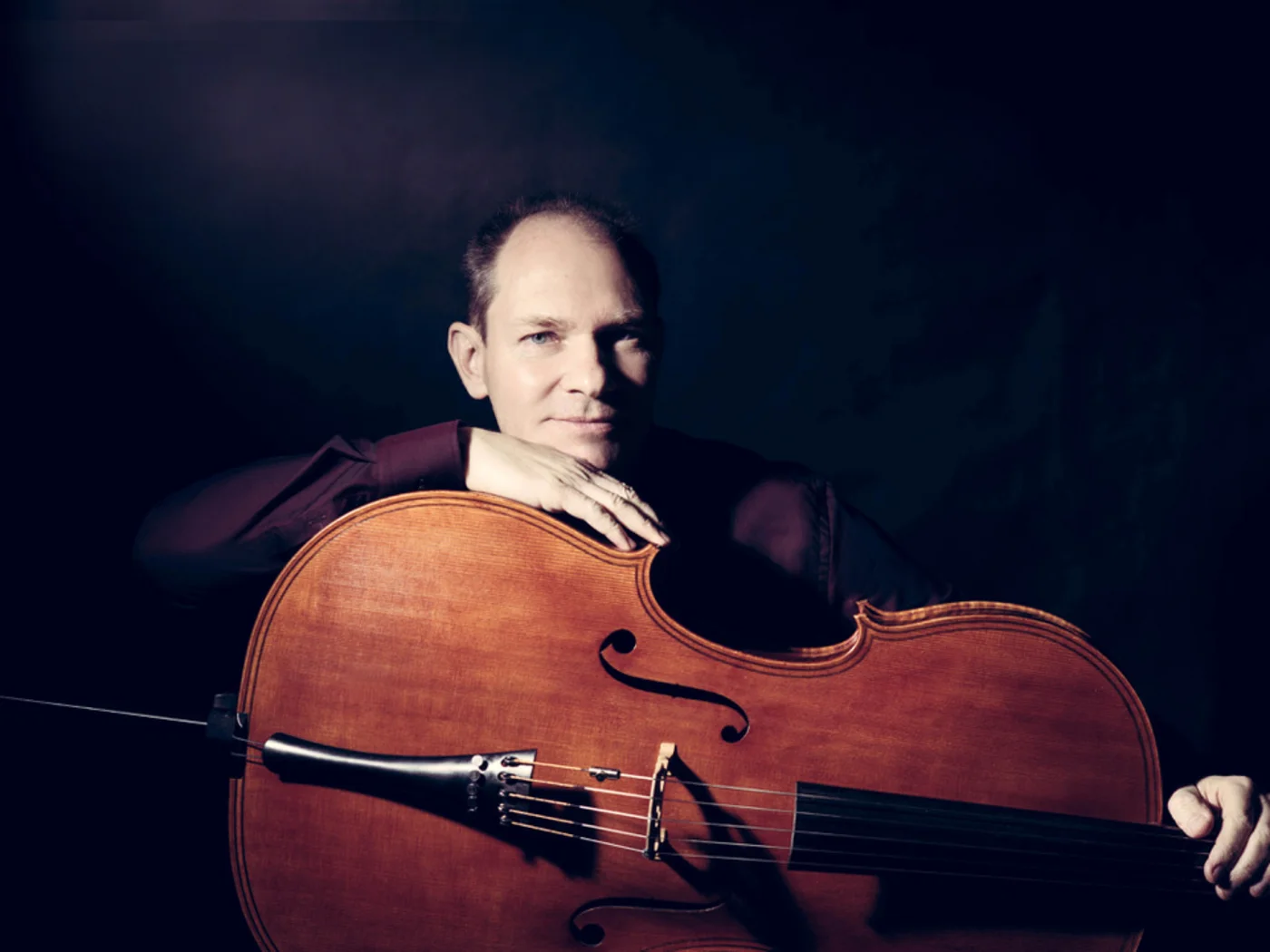 Die Schlossevents Mann mit einem Cello vor dunklem Hintergrund