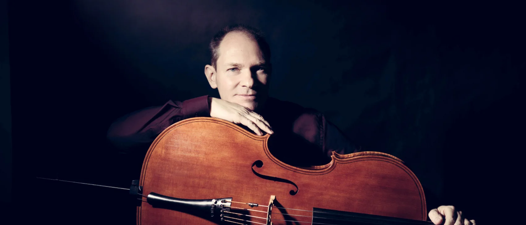 KonzertKULTur und Krippenausstellung Mann mit einem Cello vor dunklem Hintergrund