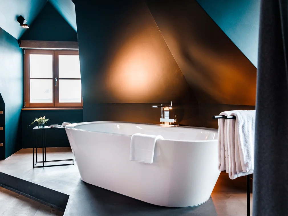 Modern freestanding bathtub in stylish bathroom with soft warm lighting