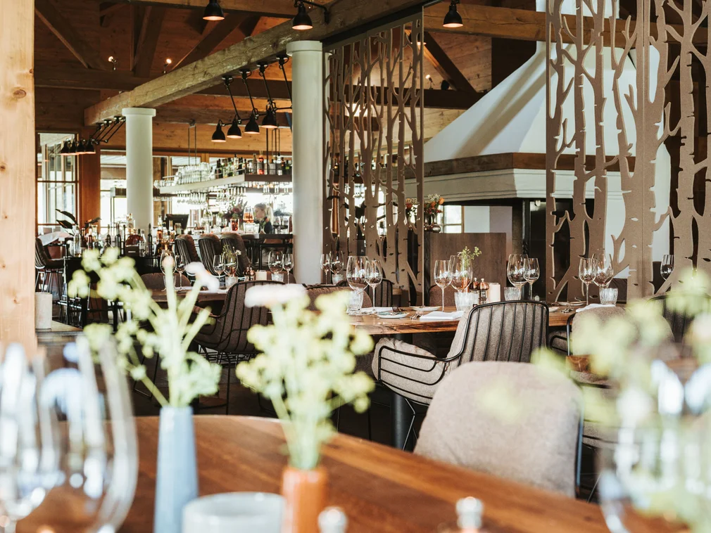 Cozy restaurant with wooden tables, chairs, and elegant table settings