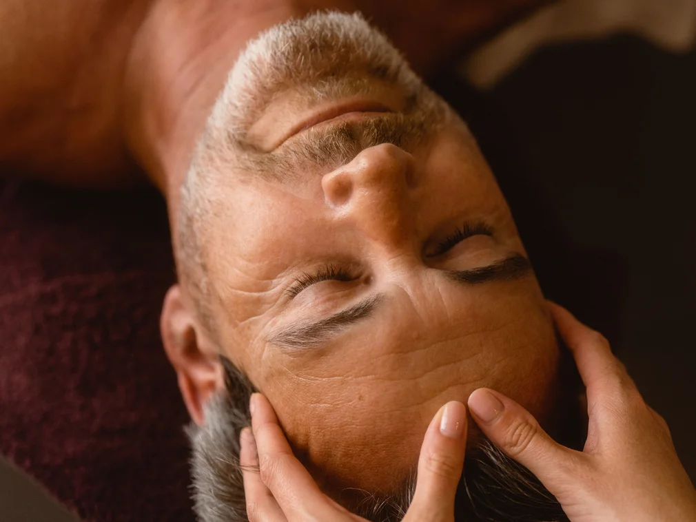 Man relaxing while receiving a head massage