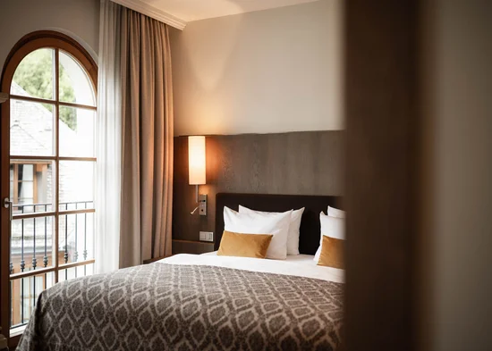Gemütliches Hotelzimmer mit Doppelbett und Balkonfenster